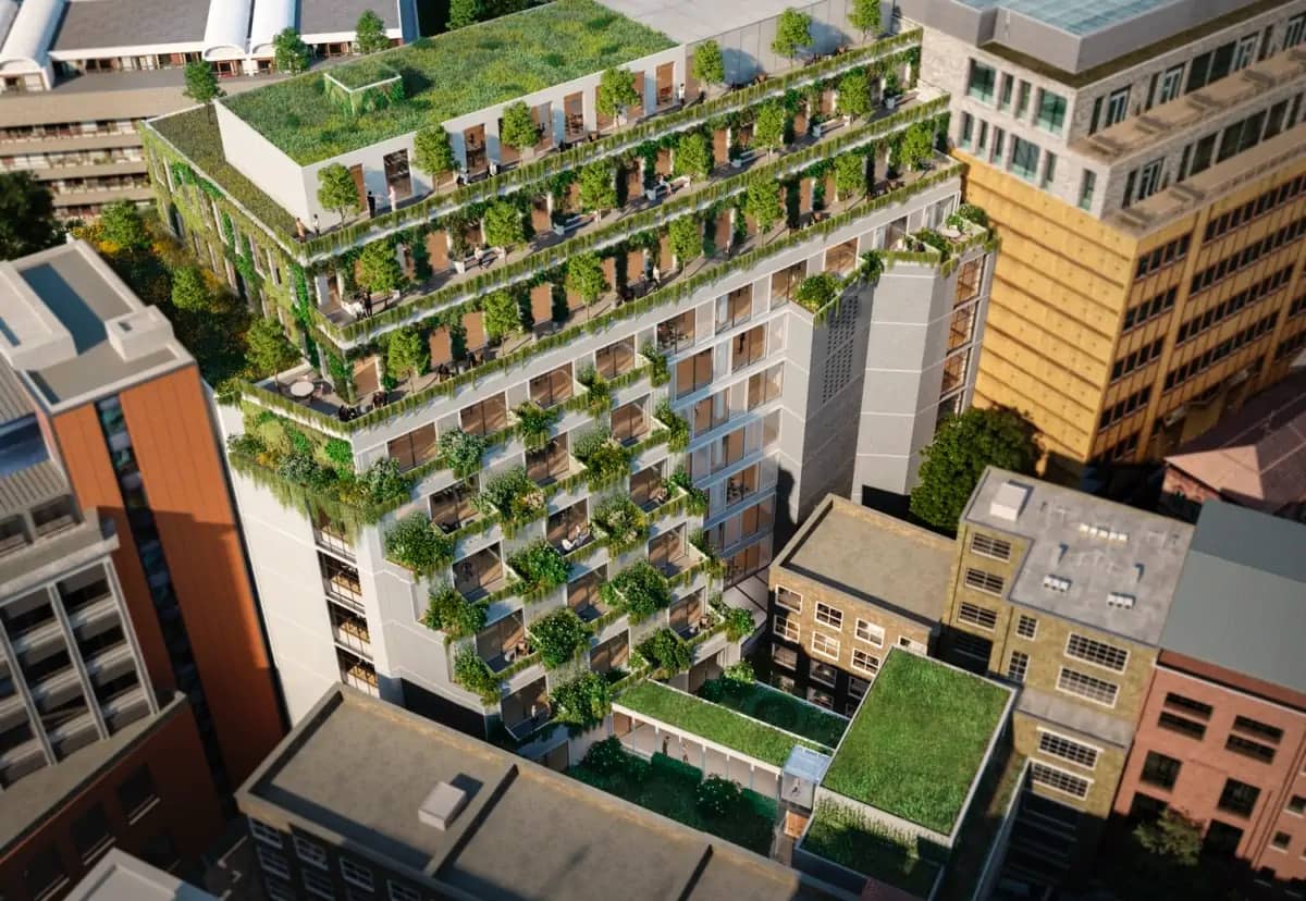 Aerial view of a modern urban building incorporating high levels of greenery, featuring extensive green roofs, vegetated terraces, and façade-integrated planting. This design enhances the Urban Greening Factor (UGF), improving biodiversity, air quality, and thermal regulation in a dense city environment.