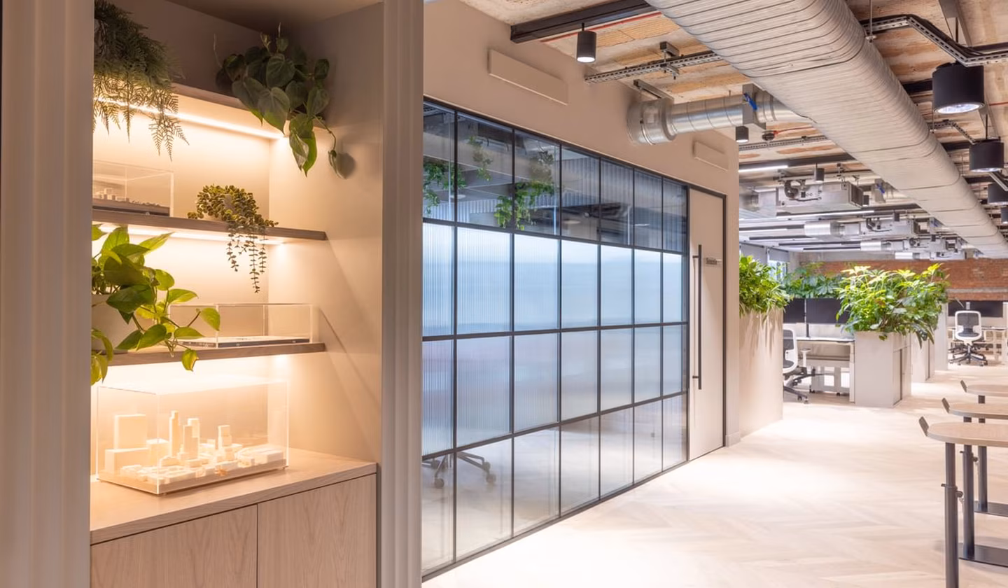 An office alcove with small wooden models, and hanging shelf office planting